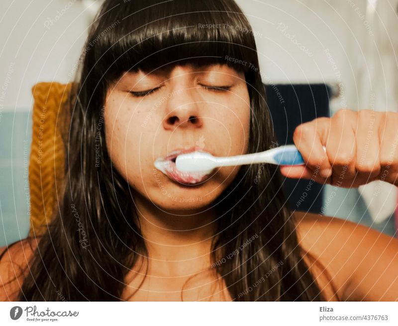 Müde Frau am Morgen mit geschlossenen Augen beim Zähneputzen müde morgens Bad zahnhygiene Zahnpflege Zahnbürste geschlossene Augen Porträt verschlafen