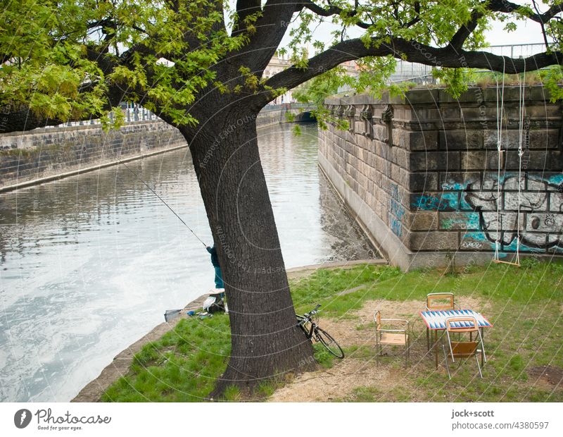 idyllischer Angelplatz am Kanal  mitten in Berlin Spreekanal Grünfläche Stadtzentrum Berlin-Mitte Ast Schaukel Tisch Stühle Oase Uferbefestigung Mauer verdeckt