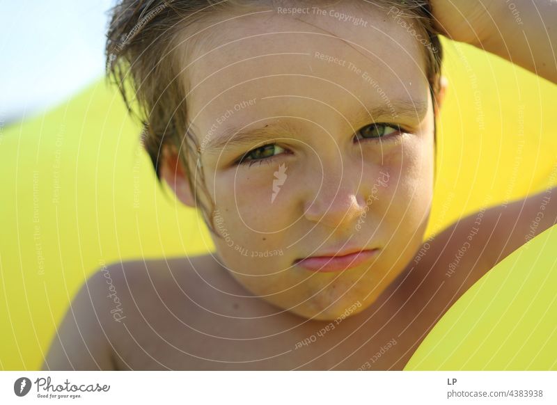 Junge am Strand auf gelbem Hintergrund mit zweifelndem Blick geheim Zufriedenheit geheimnisvoll jugendlich einzigartig Wandel & Veränderung Identität