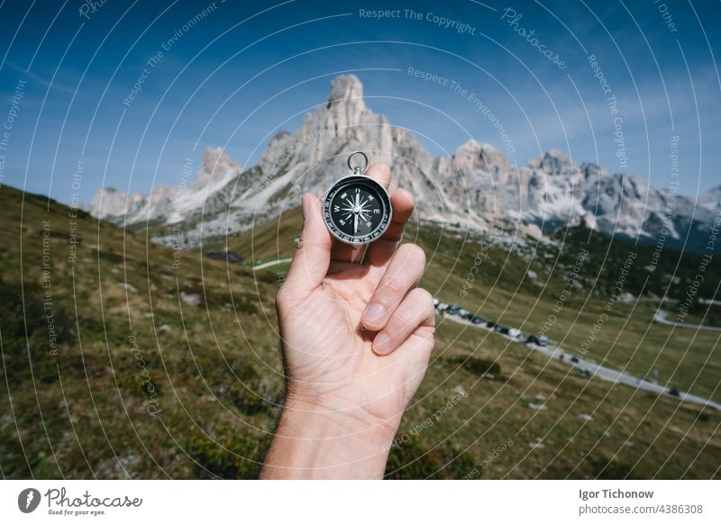 Hand hält Kompass gegen Passo Giau Berge im Hintergrund in Dolomiten Alpen, Italien. Reise Abenteuer Konzept passo giau Tourismus Gipfel Tor Landschaft Ansicht