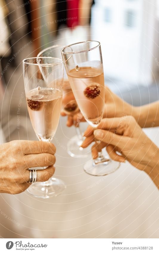 Schöne Frauenhände halten Gläser mit Champagner oder Rosenwein. Nahaufnahme. Frauen stoßen mit Gläsern an. Neujahrsfeier, Veranstaltung oder Party. Weichzeichner. Menschliche Hände. Vertikale Aufnahme