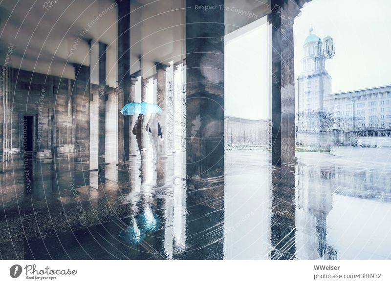 An einem kalten und regnerischen Tag läuft die junge Frau mit einem Regenschirm durch die Passage einer Großstadt nass kühl feucht Mädchen Säulen Stadt glänzen