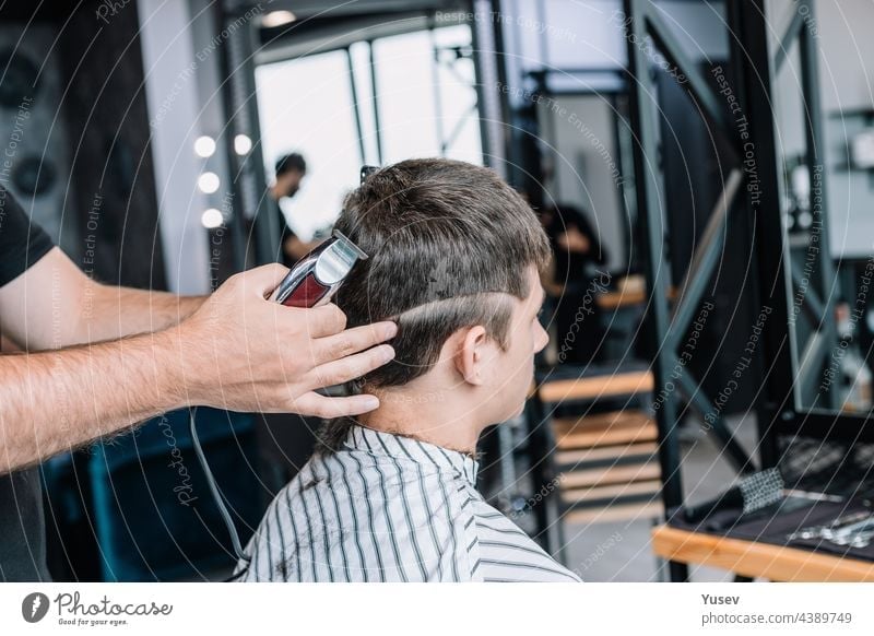 Friseur macht einem jungen Mann einen modischen, stilvollen Haarschnitt. Barbershop. Professionelle Männer Rasur und Haarschnitt, Haarpflege. professionell
