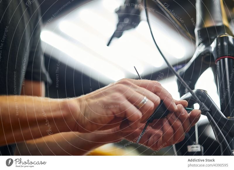 Mechaniker repariert Bremskabel eines Fahrrads in der Werkstatt Mann Kabel Bremse fixieren Reparatur Dienst männlich Arbeit Gerät professionell Job Metall