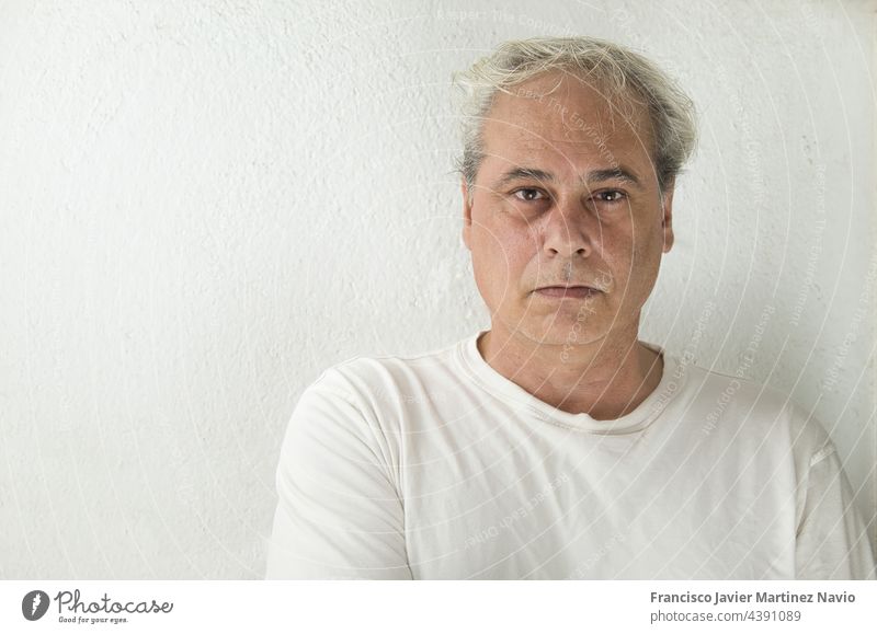 Porträt eines reifen Mannes mit grauem Haar in weißem Hemd auf weißem Hintergrund, der in die Kamera schaut Textfreiraum graue Haare Erwachsener Nahaufnahme