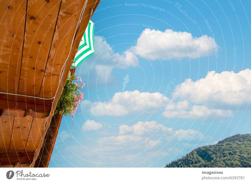 Balkonien. Balkon mit Sonnenschirm und Wolkenhimmel. Entspannen auf einem blühenden Balkon im Sommer. Sommerferien Urlaub zu Hause. zu Hause entspannen