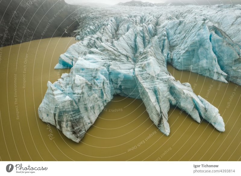 Luftaufnahme der blau gefärbten Gletscherzungenwand von oben und der schlammigen Gletscherwasserlagune in Fjallsarlon, Island Lagune glazial Antenne Wasser