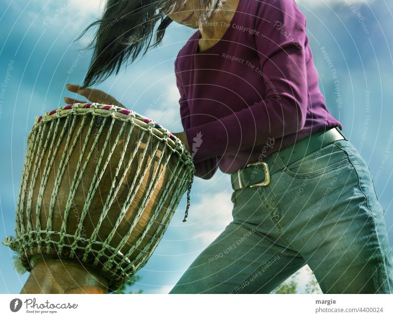 Eine Frau trommelt Djembe Trommel Schlagzeug Musik Rhythmus Schlagzeuger Instrument schlagen Takt Konzert gutaussehend Klang üben Musiker live Himmel Wolken