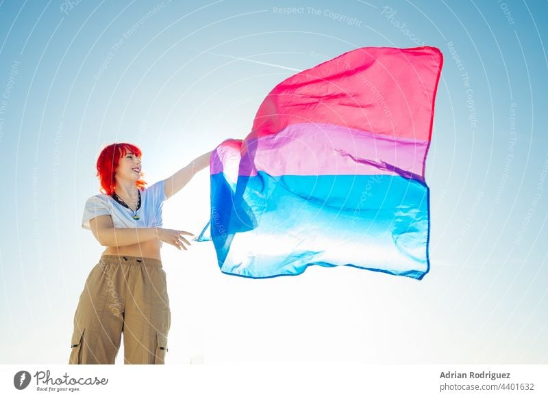 Frau hält die bisexuelle Regenbogenflagge mit dem blauen Himmel im Hintergrund Fahne lgbt Homosexualität Stolz lesbisch Rechte lgbtq Liebe schwul Symbol