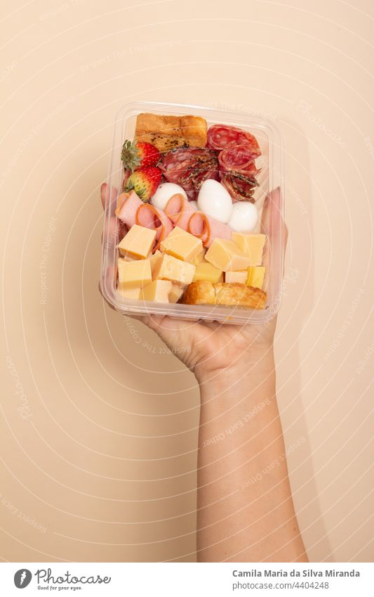 Lunchbox mit Käse, Schinken, Speck, Salami und Eiern in der Hand. Set mit Gourmet-Snacks. Amuse-Gueule Hintergrund Kasten Brot Küche lecker Diät essen