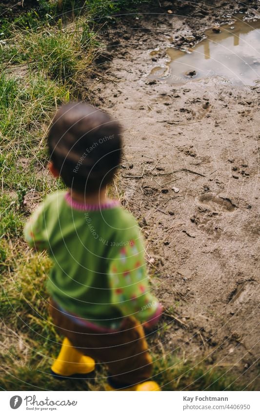 Junge mit Gummistiefeln steht vor einer Schlammpfütze Jungen sorgenfrei kaukasische Ethnizität Kind Kindheit niedlich Tag Genuss Spaß Fröhlichkeit horizontal