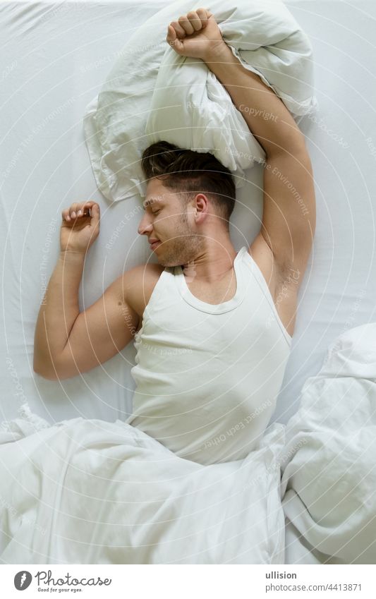 Schlafenszeit. Draufsicht auf einen muskulösen jungen Mann im Hemd, der sich morgens im Bett ausstreckt, Raum kopieren Top Ansicht Dehnungen wach Morgen