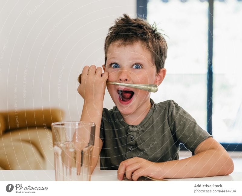 Lustiger Junge spielt mit Löffel in der Küche spielen Spaß haben Schnurrbart unterhalten lustig Kind Kindheit niedlich Tisch heimwärts bezaubernd Glück