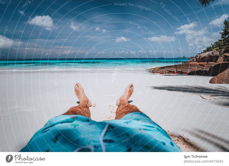 POV von männlichen tragen Badeshorts mit gebräunten Beinen auf Paradies weißen Sand tropischen exotischen Strand mit Blick auf türkisblauen Ozean. Reisen Urlaub Urlaub Konzept