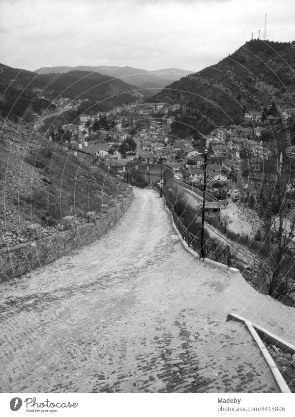Straße bergab ins Tal zwischen hohen Bergen in der Stadt Göynük in der Provinz Bolu in der Türkei, fotografiert in klassischem Schwarzweiß Heimat Zuhause Land