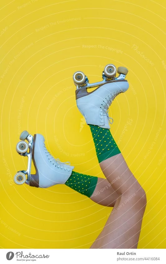 Frau mit Vintage-Quad-Rollschuhen und grünen Socken auf gelbem Hintergrund Rolle Schlittschuhe Spaß Klinge Beine Sport Sommer altehrwürdig vierfach Lifestyle