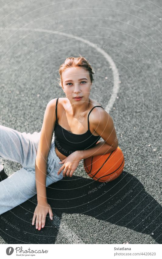 Porträt eines charmanten Mädchens auf einem Sportplatz in einem Park oder einer Schule mit einem Basketball nach einem Spiel oder Training Ball Spieler