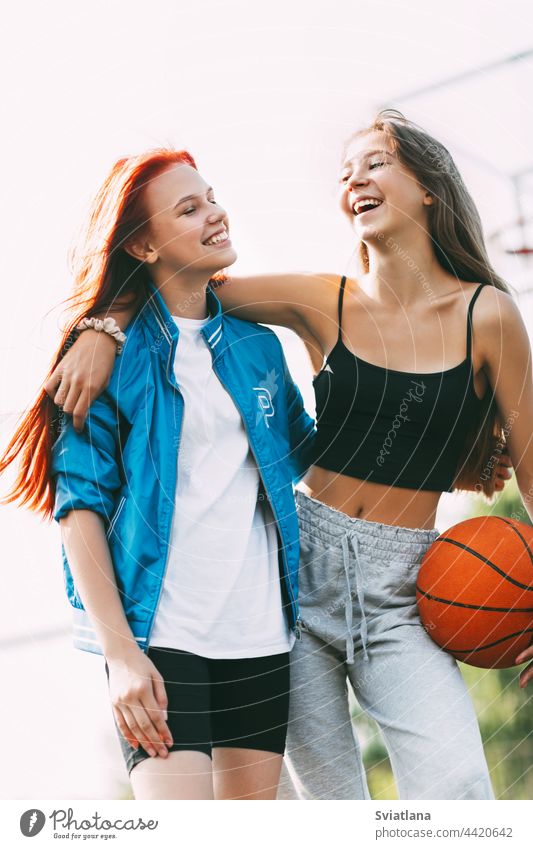 Zwei lustige Mädchen mit einem Basketball umarmen sich nach einem Spiel oder Training. Das Konzept von Sport und Freundschaft Gericht Ball Beteiligung