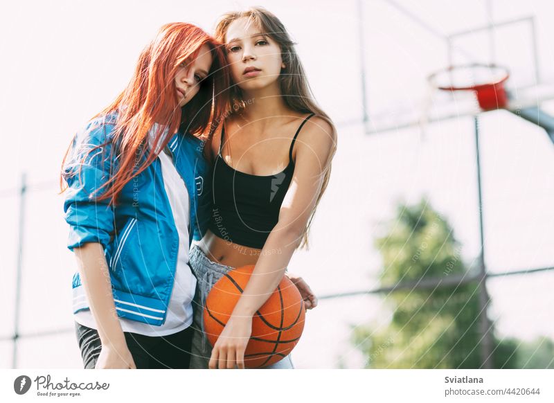 Porträt von zwei charmanten Mädchen mit einem Basketball auf dem Sportplatz. Freundschaft, beste Freunde, Sport Gericht Ball Beteiligung Basketballplatz