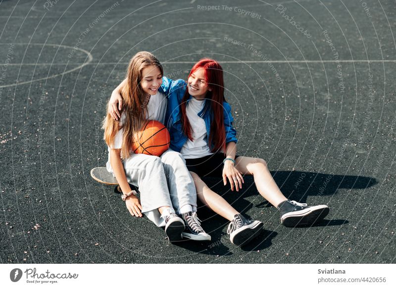 Ein paar Teenager-Mädchen entspannen sich nach einem Spiel auf einem Sportplatz mit Basketball-Lifestyle und unterhalten sich. Das Konzept des Sports und eines gesunden Lebensstils