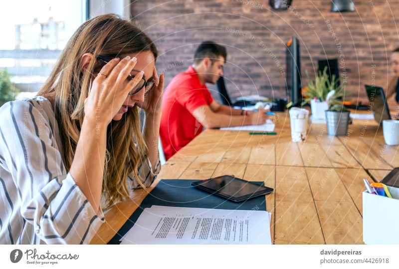 Gestresste Geschäftsfrau mit Händen auf dem Kopf gestresst bei der Arbeit Hände auf dem Kopf belastet Kopfschmerzen überarbeitet Arbeitsüberlastung Business