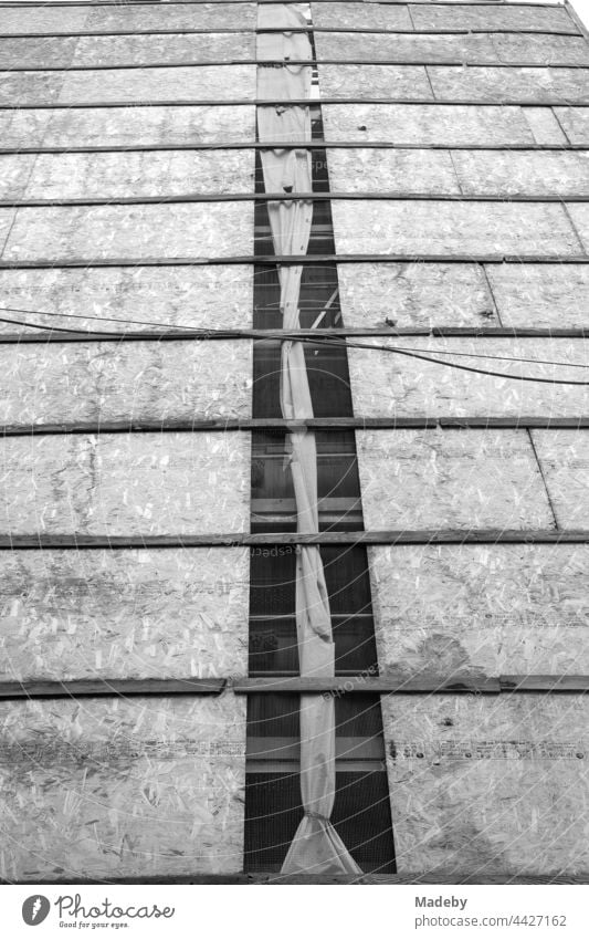 Fassadenverkleidung aus Spanplatten und alte Stromkabel vor der Fassade eines Altbau im Galataviertel im Stadtteil Beyoğlu in Istanbul am Bosporus in der Türkei, fotografiert in klassischem Schwarzweiß