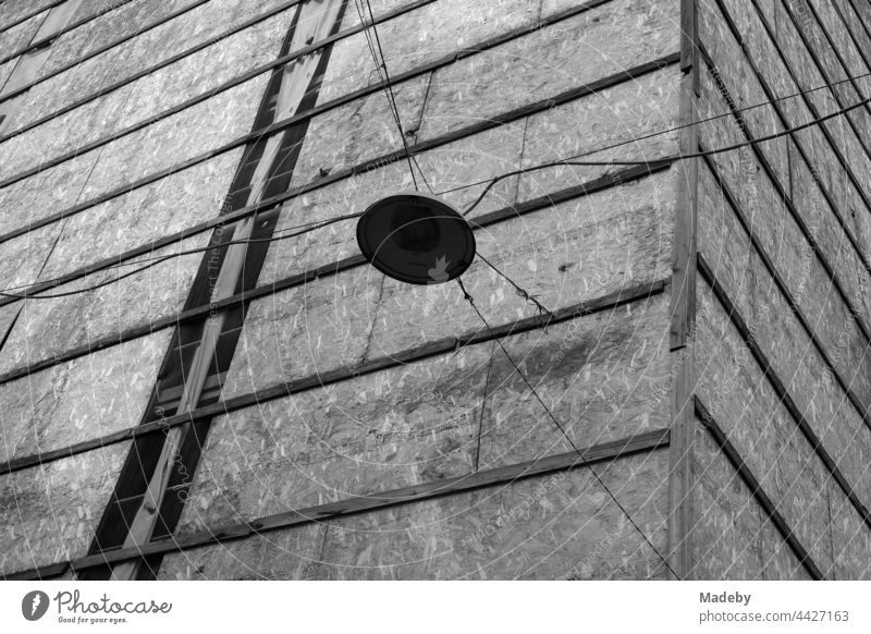 Straßenbeleuchtung an alten Stromkabeln vor einer Fassadenverkleidung mit Spanholzplatten im Galataviertel im Stadtteil Beyoğlu in Istanbul am Bosporus in der Türkei, fotografiert in neorealistischem Schwarzweiß
