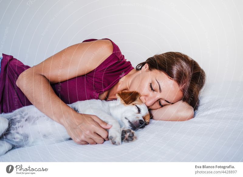 junge kaukasische Frau zu Hause ruht auf dem Bett mit niedlichen Jack Russell Hund. Haustiere, Liebe und Entspannung jack russell schlafen sich[Akk] entspannen