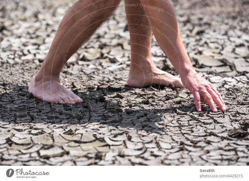 nackte Füße einer Person auf trockenem Boden ohne Pflanzen in Nahaufnahme Hintergrund schlechte Ökologie Barfuß Klima Risse Krise wüst Desaster Dürre trocknen