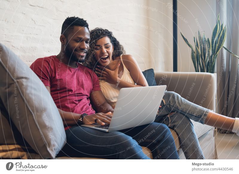 Ein Paar benutzt einen Laptop, während es zu Hause auf der Couch sitzt. heimwärts Mann Frau zwei Lifestyle Zusammensein Sofa Partnerschaft Freund Freundin