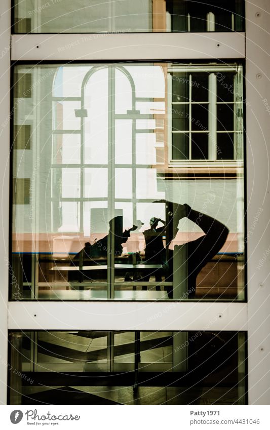 Menschliche Silhouetten vor einer geometrischen Fassade reflektieren in einer Glasscheibe | Ordnung im Chaos Fenster Reflektion Spiegelung