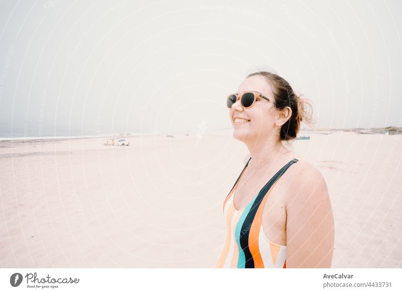 Junge Frau in einem Badeanzug und Sonnenbrille lächelt während eines sonnigen Tages am Strand, Freiheit und Urlaub Konzept, Kopie Raum Spaß Badebekleidung