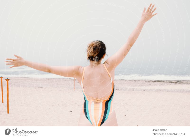 Junge Frau in einem Badeanzug zurück, Springen und Feiern während eines sonnigen Tages am Strand, Freiheit und Urlaub Konzept, Kopie Raum Spaß Badebekleidung