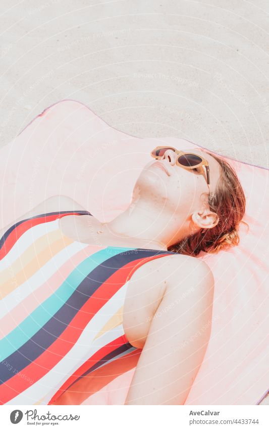 Bild von oben von einer jungen Frau in einem bunten Badeanzug ein Sonnenbad nehmen, während mit der Sonnenbrille, Urlaub und Erholung Konzept. Social Media Marketing, moderne Low-Cost-Reisen