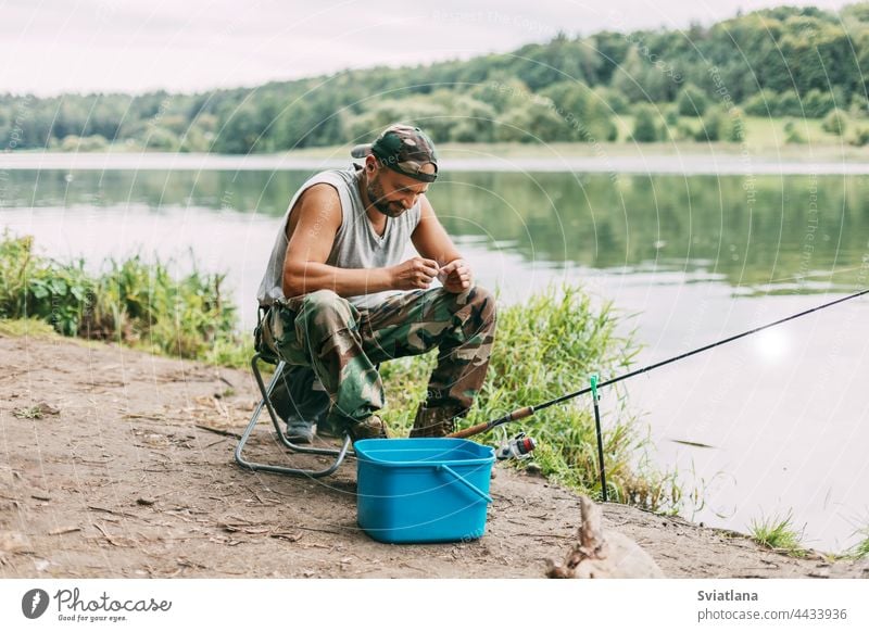 Ein junger Angler fängt Fische in einem See oder Fluss, bereitet Angelgerät und Köder vor. Hobbys, Wochenenden, Angeln Fischen Wasser Fischer Erwachsener Sitzen