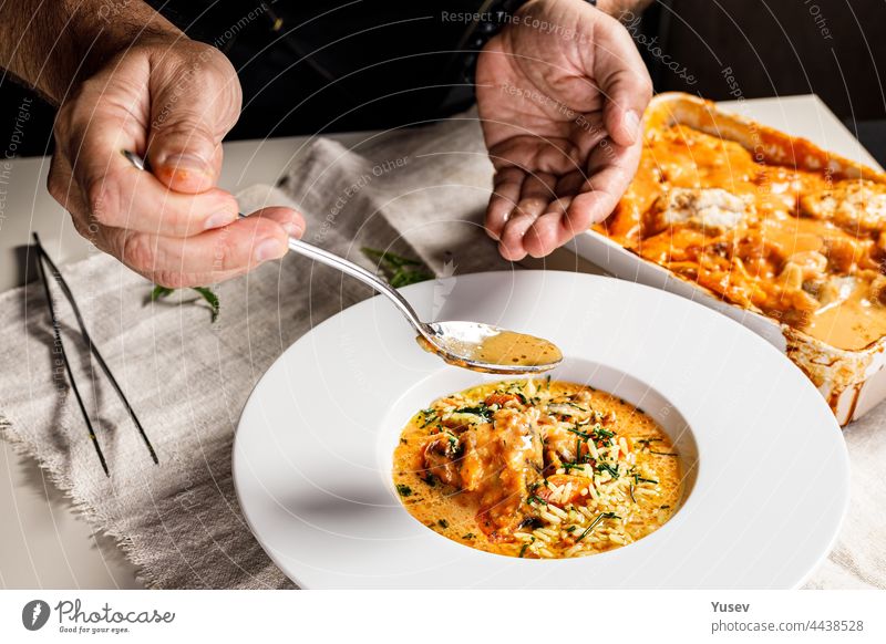 Authentische spanische Paella mit Kabeljau und Muscheln. Ein traditionelles mediterranes Gericht mit Meeresfrüchten. Der Chefkoch bereitet das Gericht zu. Ein Restaurant serviert das Gericht. Nahaufnahme. Menschen bei der Arbeit. Körperteile