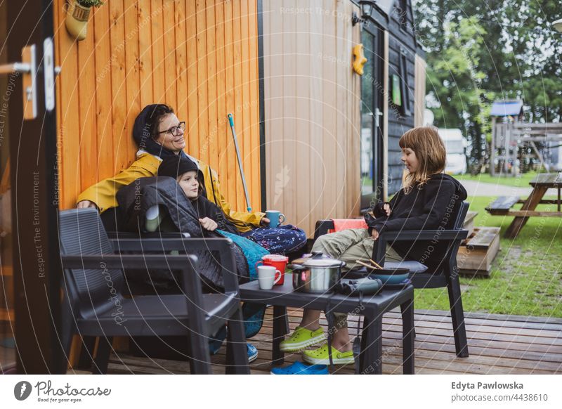 Mutter und Kinder im Gespräch vor der Holzhütte auf dem Campingplatz echte Menschen authentisch Eltern Zusammensein Liebe hölzern Kabine Haus Familie Feld