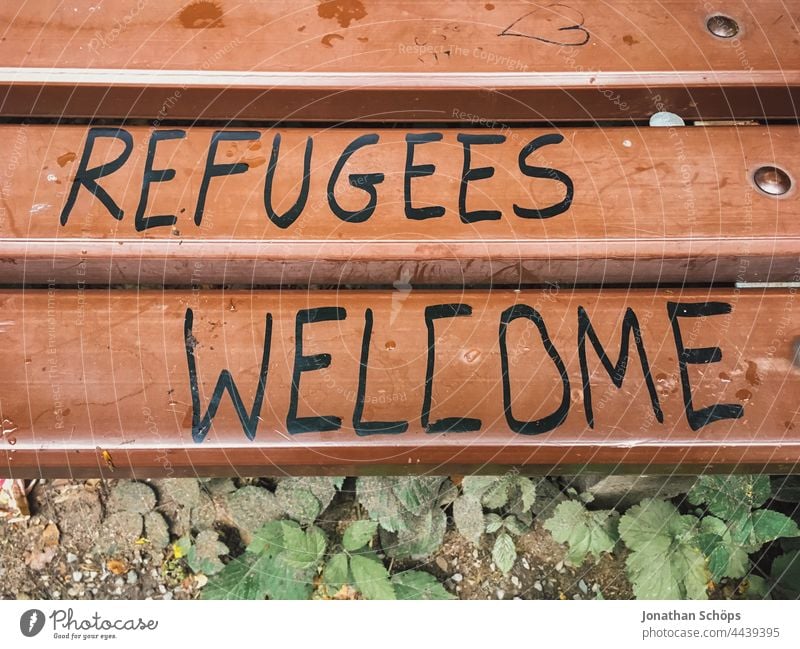 Refugees Welcome, Flüchtlinge willkommen als Schrift auf einer Bank Wörter Wort Aussage Aufforderung auffordern Typografie Typographie Buchstaben geschrieben
