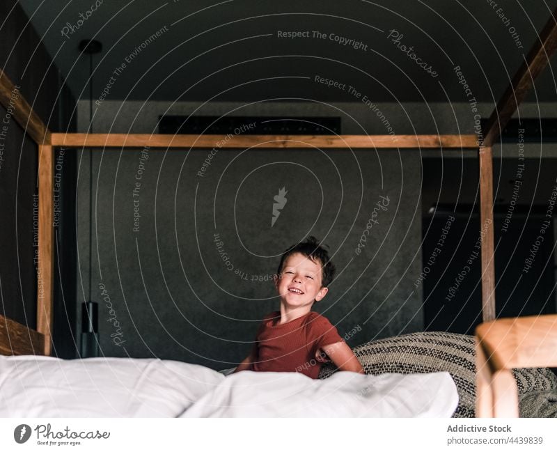 Fröhlicher Junge auf Himmelbett Kind Spaß haben Schlafzimmer Schutzdach Bett hängen heiter unterhalten niedlich Kindheit wenig positiv sorgenfrei Lächeln