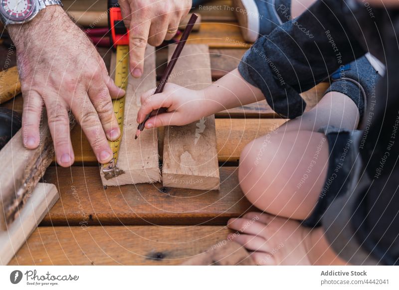Crop-Vater mit Sohn beim Messen von Holzbrettern messen Schiffsplanken Holzarbeiten diy Klebeband Bleistift Basteln Hilfsbereitschaft Mann präzise Junge