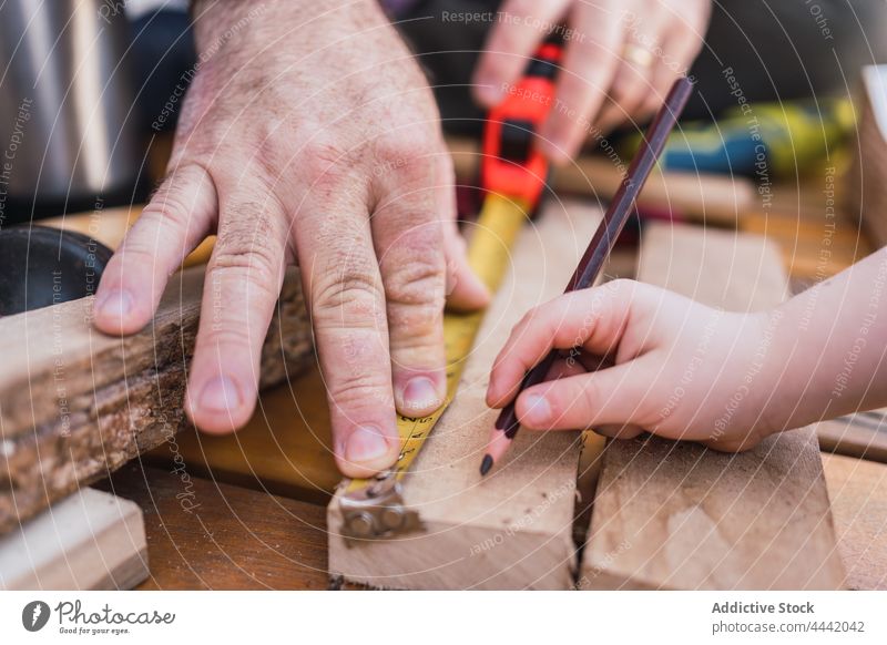 Crop-Vater mit Sohn beim Messen von Holzbrettern messen Schiffsplanken Holzarbeiten diy Klebeband Bleistift Basteln Hilfsbereitschaft Mann präzise Junge