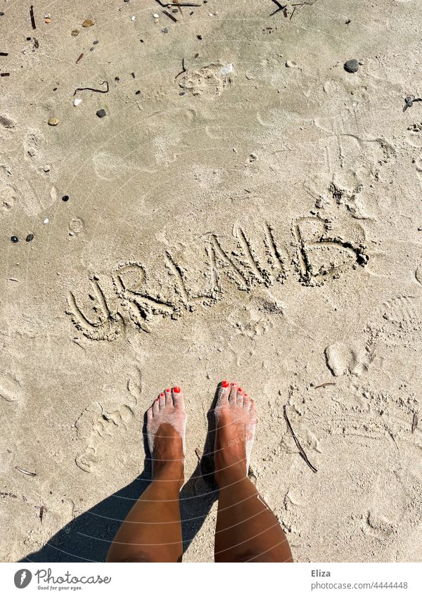 Füße stehen am Strand vor dem, in den Sand geschriebenen, Wort Urlaub Ferien & Urlaub & Reisen Strandurlaub Sommer Sommerurlaub Urlaubsstimmung urlaubsreif
