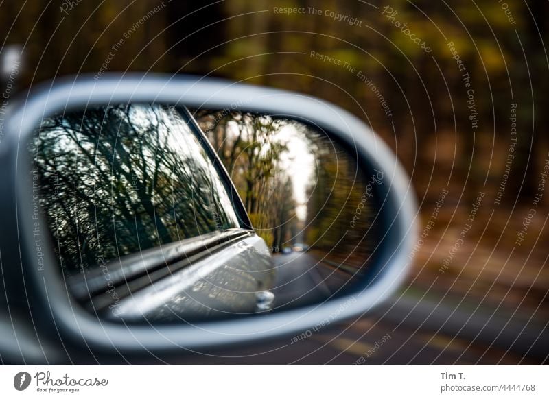 Ein Auto fährt eine Straße entlang, im Seitenspiegel spiegelt sich