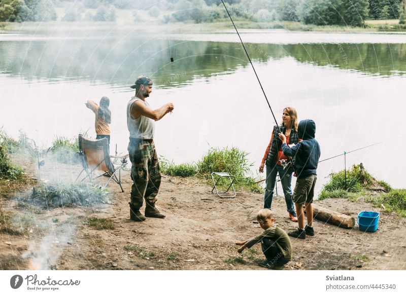 Eine glückliche Familie angelt am Ufer eines Flusses oder Sees. Zeit miteinander verbringen, Familienzeit, Familienurlaub Fischen Zusammensein Mama Tochter Sohn