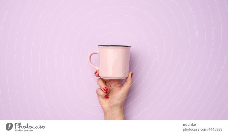 weibliche Hand hält einen rosa Keramikbecher auf einem lila Hintergrund, Pause Zeit und trinken Kaffee, Banner nach oben Erwachsener Arme Getränk blanko purpur