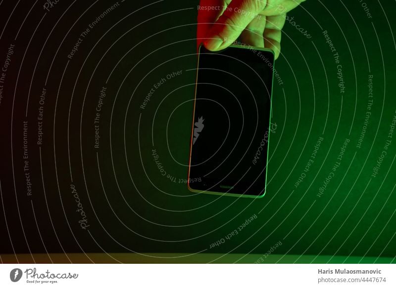 Hand hält Mobiltelefon, grüne Lichter dunkler Hintergrund süchtig App Anwendung schwarz schwarzer Hintergrund blau Funktelefon Nahaufnahme dunkel Gerät digital
