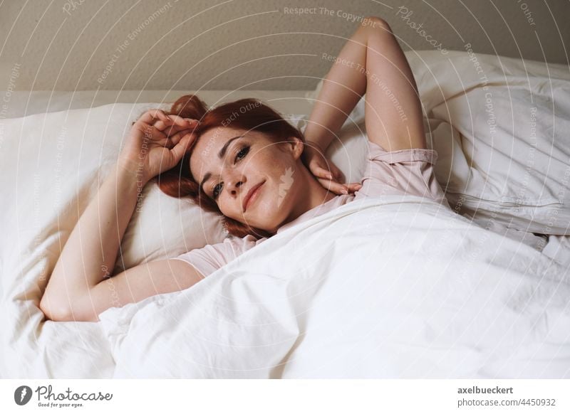glücklich lächelnde junge Frau, die nach dem Aufwachen im Bett liegt Schlafzimmer Morgen wecken Glück Lächeln heimwärts Erwachsener Person authentisch Lifestyle