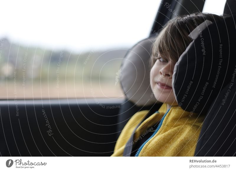 Kind sitzt im Kindersitz im Auto Alltag Verkehr Sicherheit sicher fahren Porträt Kindheit Mobilität mobil unterwegs Ausflug gelb Blickkontakt 7 Jahre Fahrt