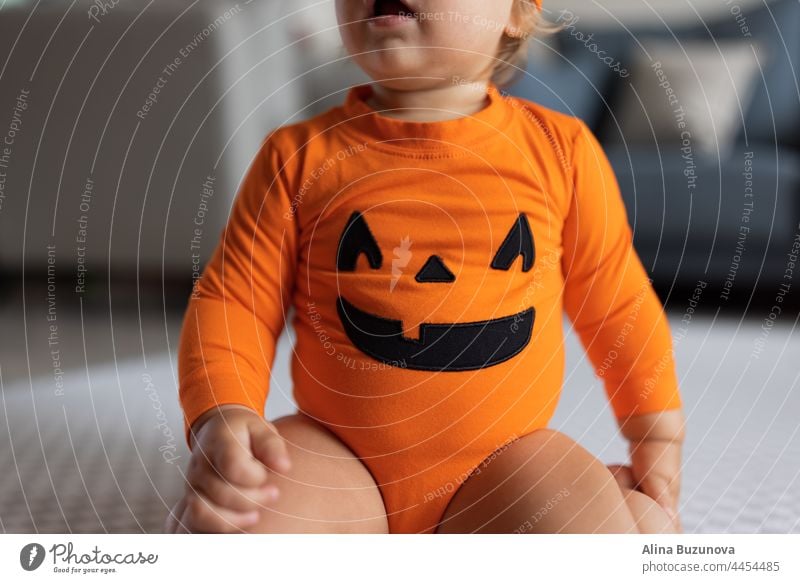 Glückliches einjähriges Baby im orangefarbenen Halloween-Kostüm zu Hause 2-3 Monate weinen Gas Gesundheit neugeboren Pflege Kolik Haut Kind Kürbis Massage