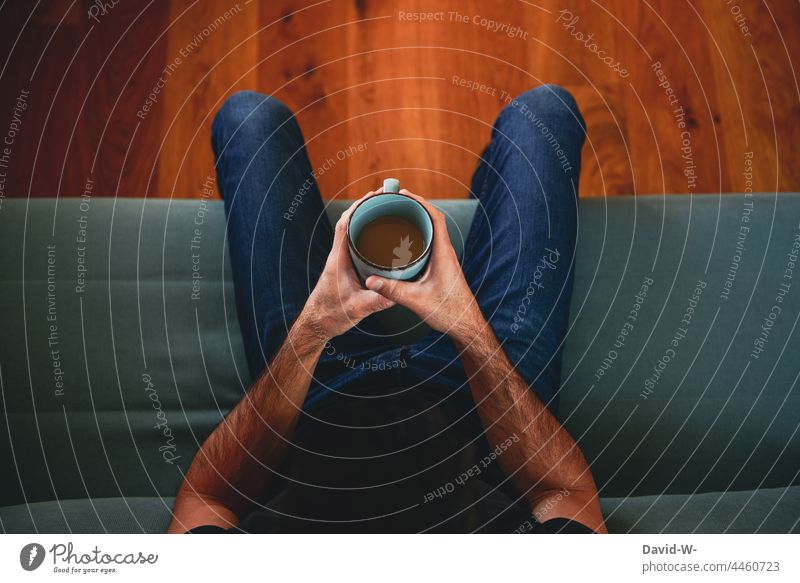 Kaffeepause - Mann hält einen Becher mit Kaffee in den Händen und sitzt auf dem Sofa Pause halten ruhe genießen sitzen Tasse Kaffeetasse